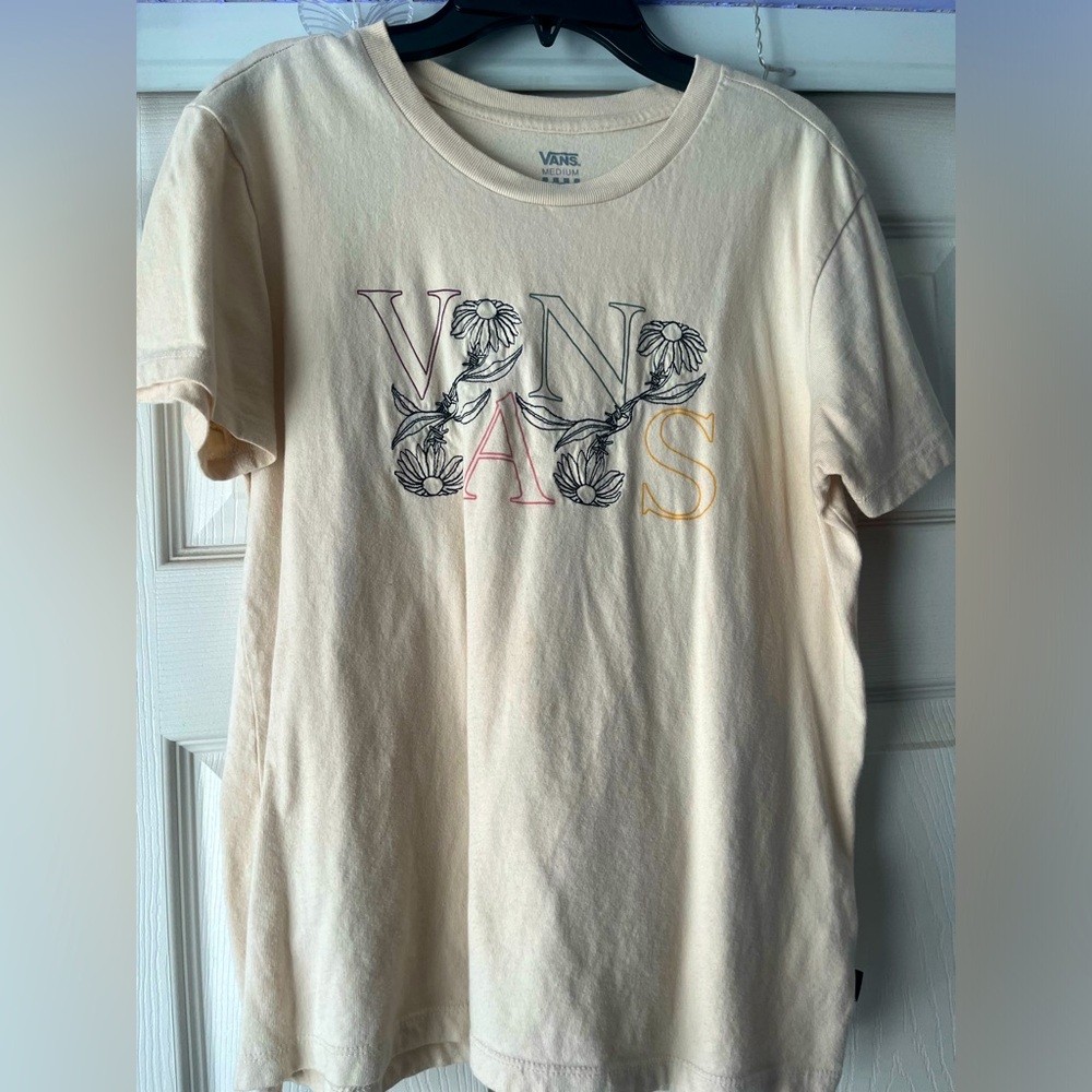 Tan tee with sewn in design on the front.